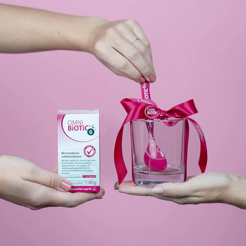 Eine OMNi-BiOTiC 6 Packung mit einem Glas und einem Löffel