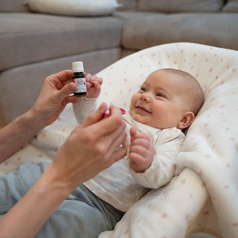 Ein lachendes Baby wird mit OMNi-BiOTiC PANDA Tropfen gefüttert