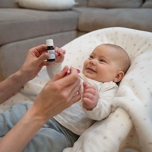 Ein lachendes Baby wird mit OMNi-BiOTiC PANDA Tropfen gefüttert