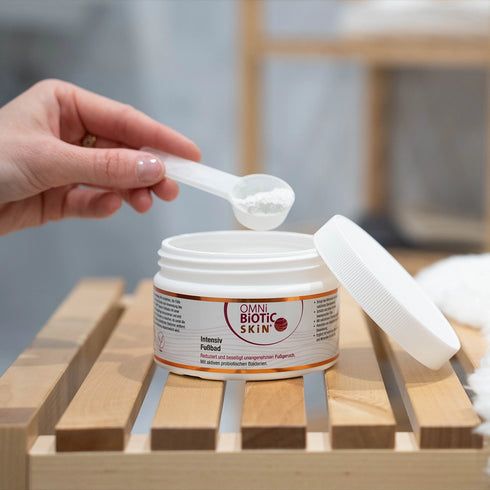 Ein Löffel OMNi-BiOTiC SKiN Intensiv-Fußbad wird aus der Packung entnommen