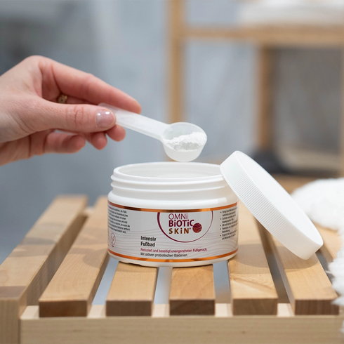 Ein Löffel OMNi-BiOTiC SKiN Intensiv-Fußbad wird aus der Packung entnommen