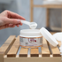 Ein Löffel OMNi-BiOTiC SKiN Intensiv-Fußbad wird aus der Packung entnommen