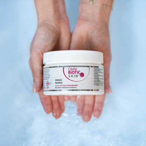 Zwei Hände halten eine Packung OMNi-BiOTiC SKiN Intensiv-Hautbad