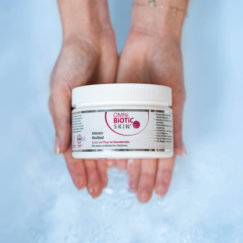 Zwei Hände halten eine Packung OMNi-BiOTiC SKiN Intensiv-Hautbad