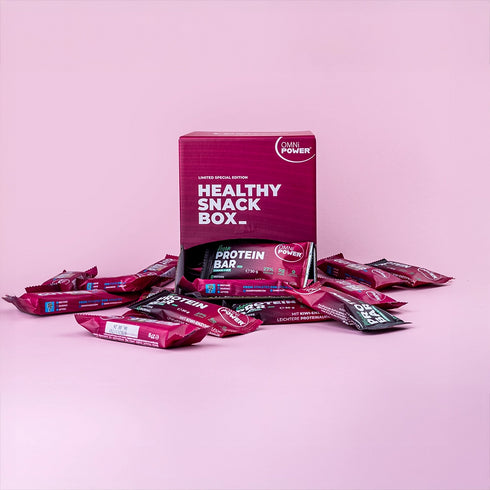 Eine offene OMNi-POWER Healthy Snack Box mit Riegeln drum herum verteilt